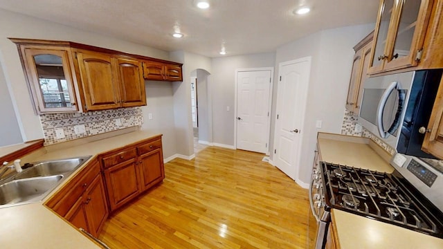 780 S Timber Ridge Dr, Nixa, MO 65714 - kitchen with stainless steel appliances, arched walkways, decorative backsplash, a sink, and glass insert cabinets