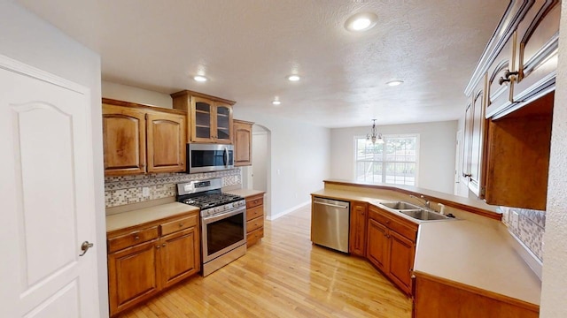 780 S Timber Ridge Dr, Nixa, MO 65714 - kitchen with stainless steel appliances, a sink, decorative backsplash, arched walkways, and light wood-style floors