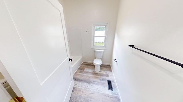 627 W Cherry St, Nevada, MO 64772 - bathroom featuring toilet, wood finished floors, a bathtub, and baseboards