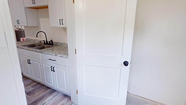 627 W Cherry St, Nevada, MO 64772 - kitchen featuring a sink, light wood finished floors, and white cabinets