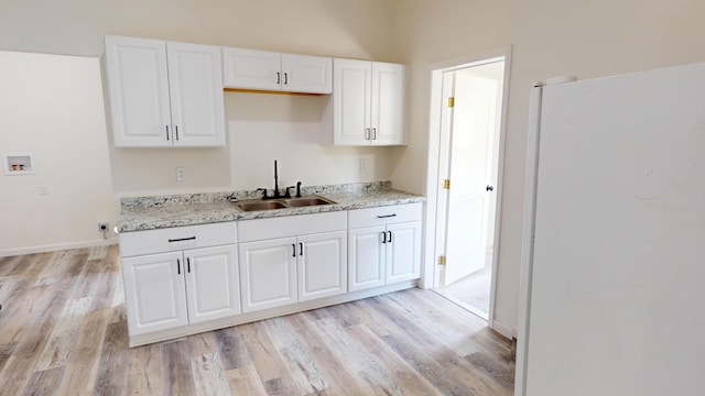 627 W Cherry St, Nevada, MO 64772 - kitchen with freestanding refrigerator, a sink, light wood finished floors, and white cabinetry