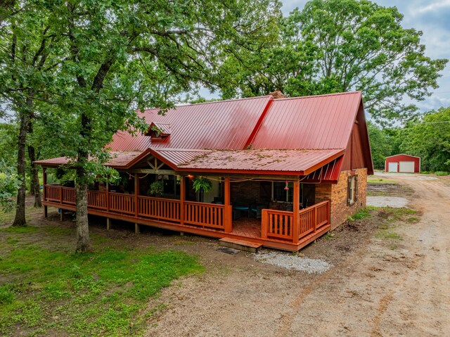 1501 NE 775th Rd, Osceola, MO 64776 - rustic home with dirt driveway, a garage, an outdoor structure, stone siding, and metal roof