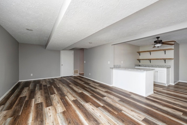 617 E SE Hills Ct, Nixa, MO 65714 - unfurnished living room with dark wood-style flooring, baseboards, a textured ceiling, and ceiling fan