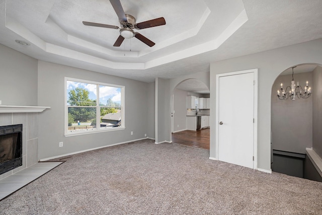 617 E SE Hills Ct, Nixa, MO 65714 - unfurnished living room featuring arched walkways, carpet flooring, ceiling fan, a raised ceiling, and a tile fireplace