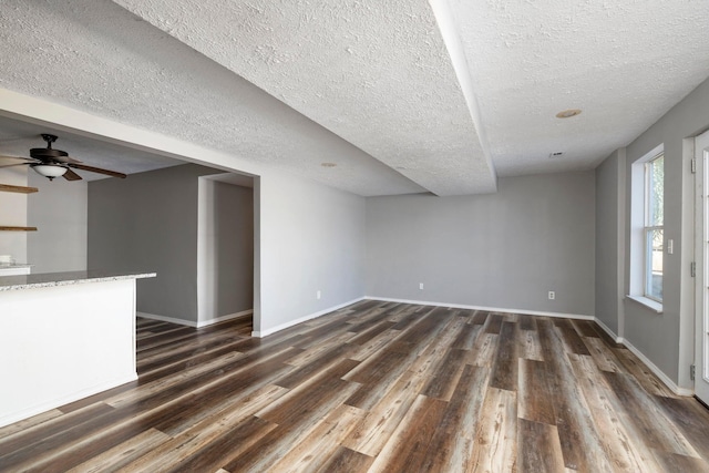 617 E SE Hills Ct, Nixa, MO 65714 - unfurnished living room featuring dark wood-type flooring, a textured ceiling, baseboards, and ceiling fan