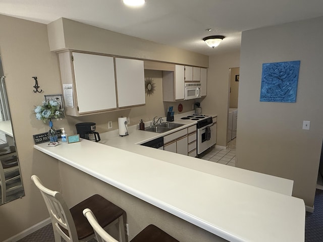 132 Highland Dr Unit 2, Branson, MO 65616 - kitchen featuring white appliances, washing machine and clothes dryer, a sink, light countertops, and a kitchen bar