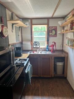 20001 Clear Lake Ter, Winona, MO 65588 - kitchen featuring dark wood-type flooring, open shelves, stainless steel microwave, and gas range oven