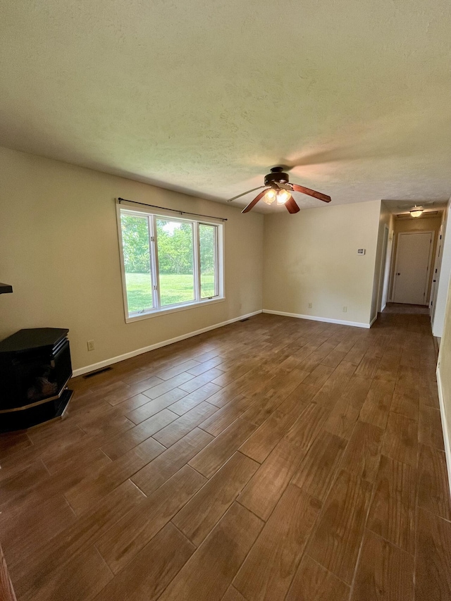 194 State Highway T, Oldfield, MO 65720 - unfurnished living room with a wood stove, ceiling fan, dark wood-style flooring, baseboards, and a textured ceiling