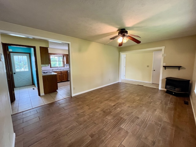 194 State Highway T, Oldfield, MO 65720 - unfurnished living room featuring a wood stove, wood tiled floors, a sink, ceiling fan, and baseboards