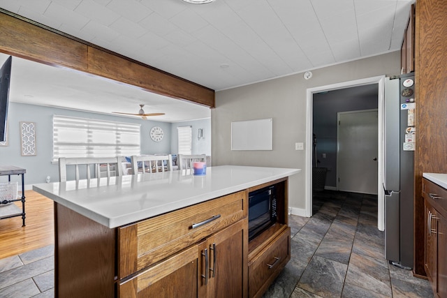 1103 4th St, Monett, MO 65708 - kitchen with black microwave, freestanding refrigerator, stone tile floors, and light countertops