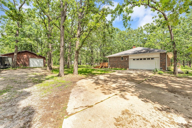 1061 Brentwood Dr, Marshfield, MO 65706 - view of home's exterior with brick siding, driveway, a chimney, an outdoor structure, and a garage