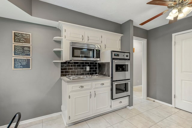 2215 E Rosebrier St, Springfield, MO 65804 - kitchen with stainless steel appliances, decorative backsplash, light tile patterned flooring, a ceiling fan, and white cabinets