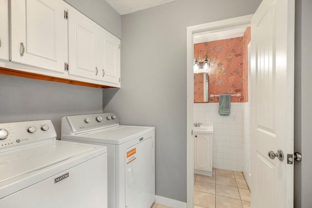 2215 E Rosebrier St, Springfield, MO 65804 - washroom featuring washing machine and clothes dryer, cabinet space, light tile patterned floors, tile walls, and a wainscoted wall