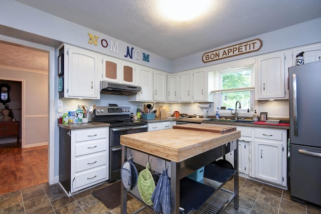 2344 E Manchester St, Springfield, MO 65804 - kitchen featuring stainless steel appliances, under cabinet range hood, dark countertops, white cabinets, and a textured ceiling