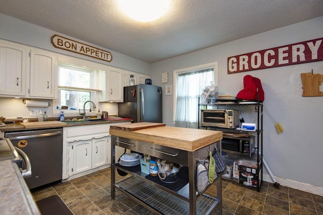 2344 E Manchester St, Springfield, MO 65804 - kitchen with appliances with stainless steel finishes, a sink, white cabinets, a textured ceiling, and wooden counters