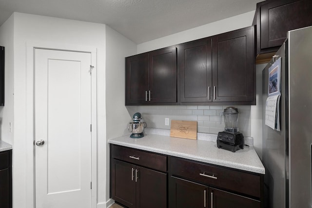 1118 E Lakota St, Nixa, MO 65714 - kitchen featuring freestanding refrigerator, light countertops, backsplash, and dark brown cabinets