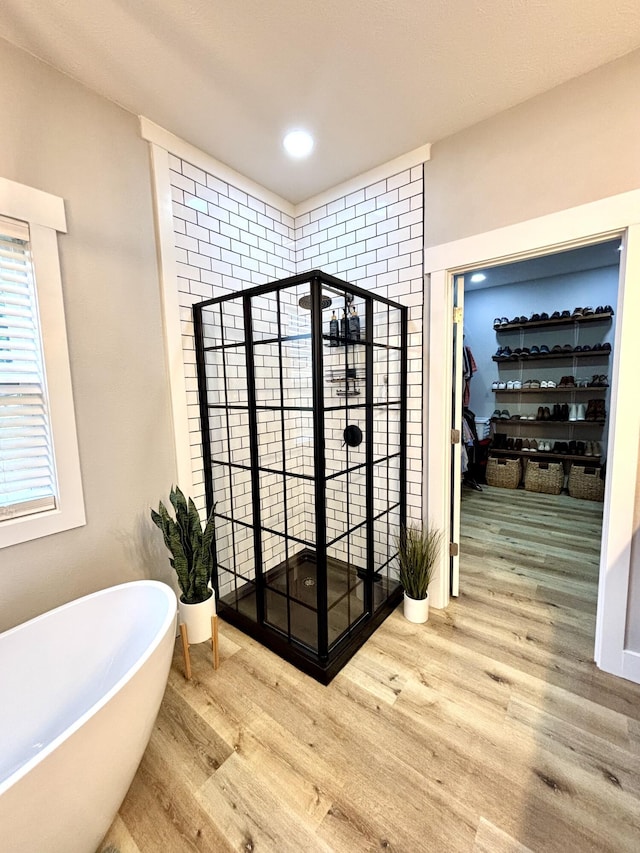 2702 Town Dr, Mountain Grove, MO 65711 - bathroom with a soaking tub, wood finished floors, a walk in closet, a stall shower, and recessed lighting