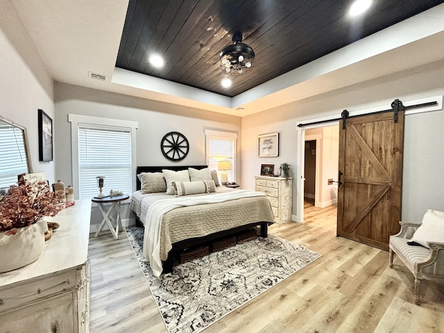 2702 Town Dr, Mountain Grove, MO 65711 - bedroom featuring a barn door, light wood finished floors, a tray ceiling, multiple windows, and recessed lighting