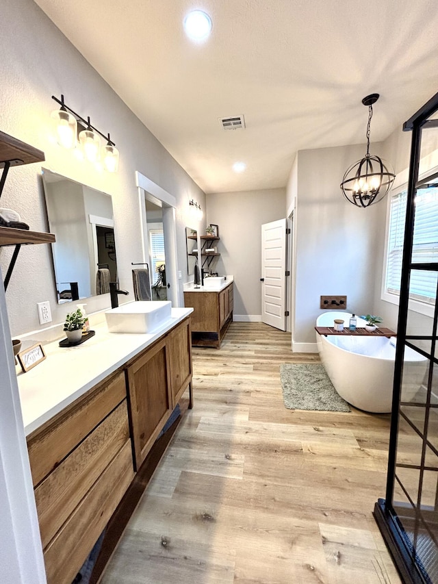 2702 Town Dr, Mountain Grove, MO 65711 - full bath featuring two vanities, a freestanding bath, wood finished floors, a chandelier, and baseboards