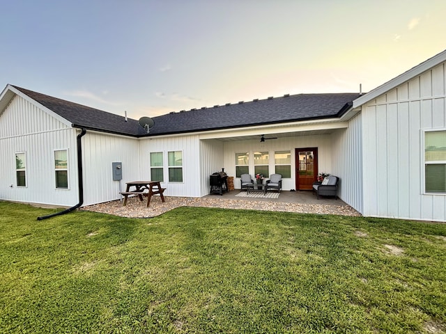 2702 Town Dr, Mountain Grove, MO 65711 - back of property at dusk featuring a patio area, a lawn, ceiling fan, roof with shingles, and board and batten siding