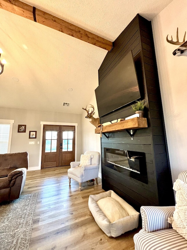 2702 Town Dr, Mountain Grove, MO 65711 - living area featuring a large fireplace, french doors, a textured ceiling, wood finished floors, and baseboards