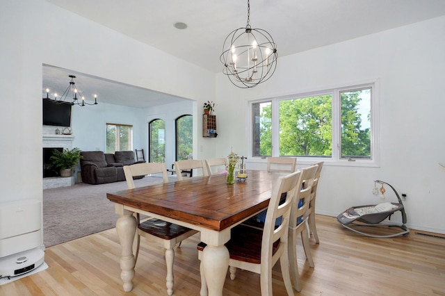 11976 N Northern Hts Dr, Brighton, MO 65617 - dining space with a chandelier, light wood finished floors, and a fireplace