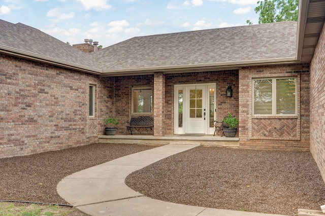 11976 N Northern Hts Dr, Brighton, MO 65617 - property entrance featuring a shingled roof, brick siding, and a chimney