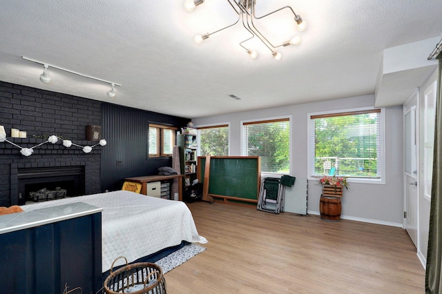 11976 N Northern Hts Dr, Brighton, MO 65617 - bedroom featuring a fireplace, multiple windows, light wood-style floors, baseboards, and a textured ceiling