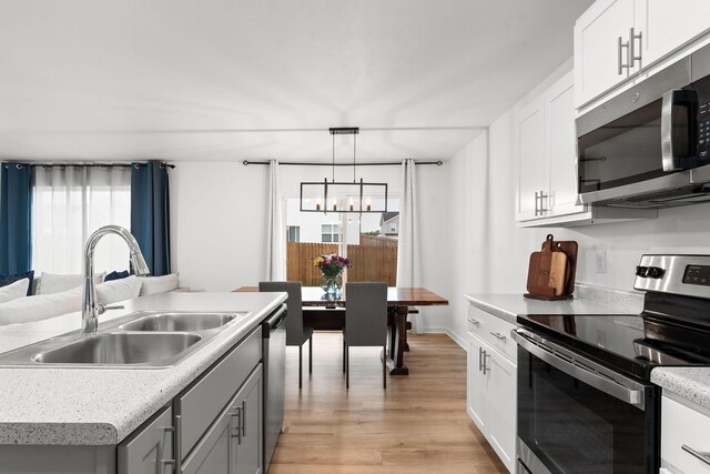 565 S Michelle Ave, Republic, MO 65738 - kitchen with stainless steel appliances, a sink, a chandelier, light wood-style floors, and light countertops