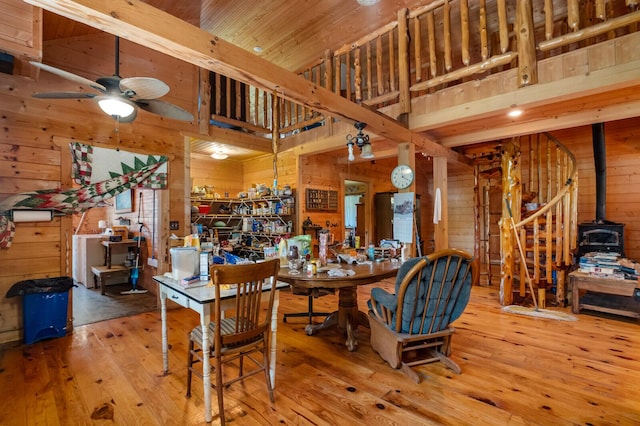 447 Flint Ln, Washburn, MO 65772 - dining room featuring wood walls, hardwood / wood-style floors, a wood stove, a towering ceiling, and ceiling fan