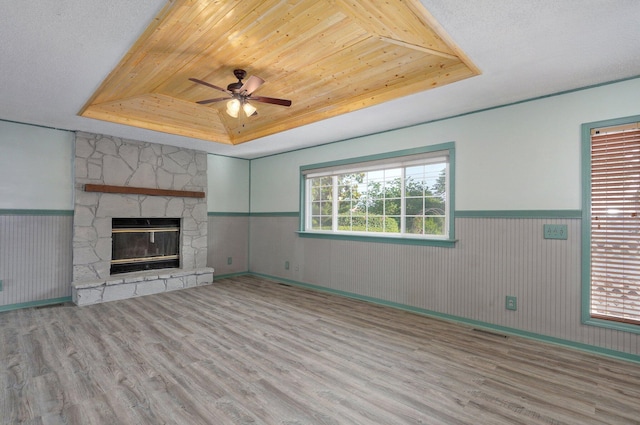 1132 Irene Ct, Nixa, MO 65714 - unfurnished living room with a tray ceiling, wood finished floors, a wainscoted wall, ceiling fan, and a fireplace