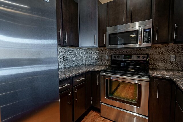 kitchen featuring appliances with stainless steel finishes, tasteful backsplash, and dark stone counters