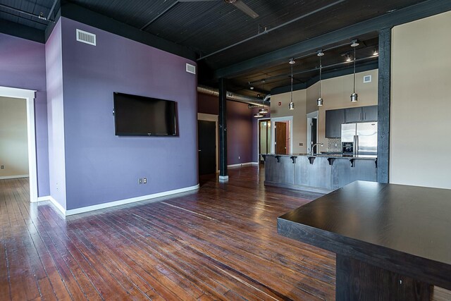 unfurnished living room featuring a high ceiling, dark wood-style floors, baseboards, a sink, and track lighting