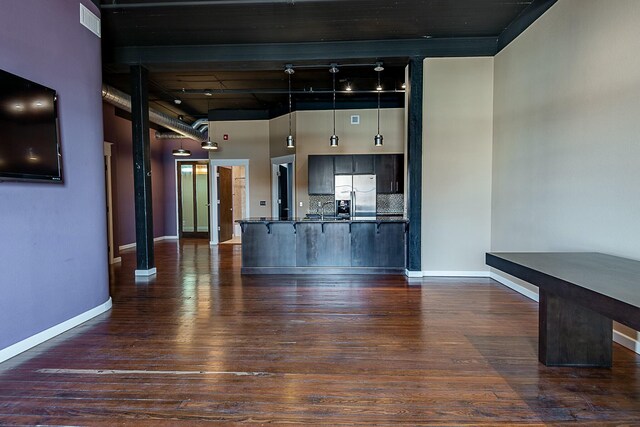 unfurnished living room featuring dark wood-type flooring, baseboards, and a towering ceiling