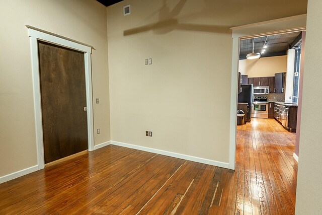 unfurnished room featuring hardwood / wood-style floors, a ceiling fan, and baseboards
