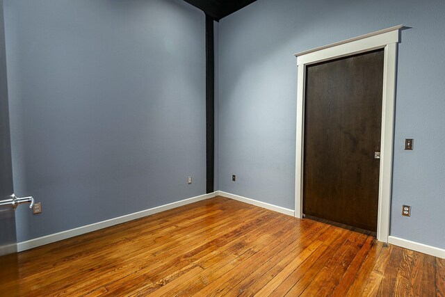 unfurnished room featuring wood-type flooring and baseboards