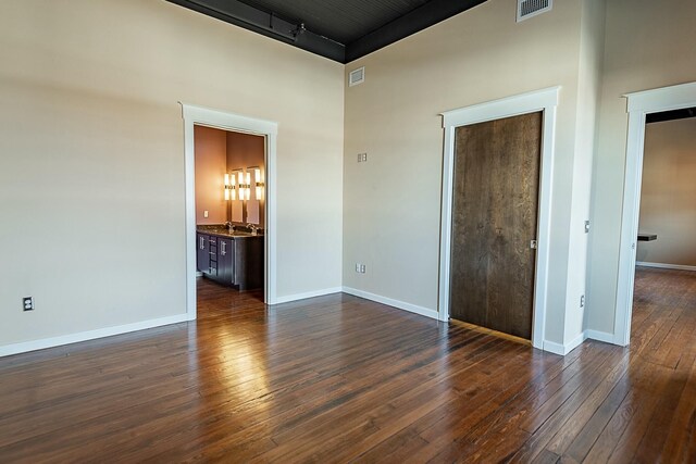 empty room featuring dark wood-style floors, baseboards, and a high ceiling