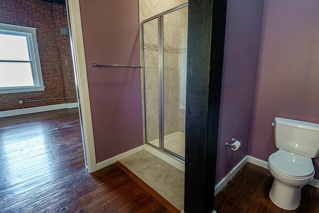 bathroom with baseboards, toilet, hardwood / wood-style flooring, and a shower stall