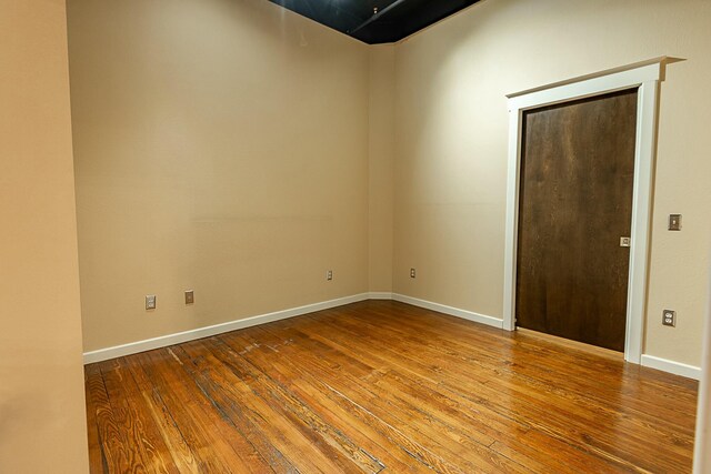 unfurnished room with hardwood / wood-style floors and baseboards