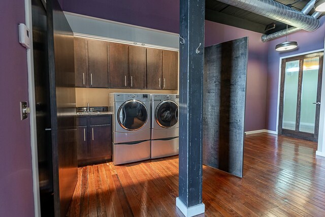 laundry room with washer and dryer, cabinet space, and wood-type flooring
