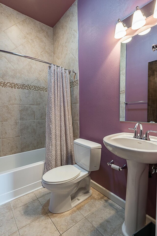 bathroom featuring toilet, tile patterned floors, shower / bath combo, baseboards, and a sink