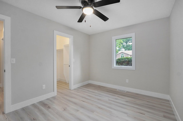 1436 W Whiteside St, Springfield, MO 65807 - unfurnished bedroom with a walk in closet, light wood-style flooring, baseboards, and ceiling fan