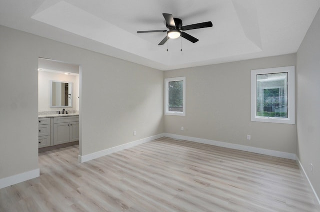1436 W Whiteside St, Springfield, MO 65807 - unfurnished bedroom with a tray ceiling, light wood finished floors, baseboards, ensuite bathroom, and a sink