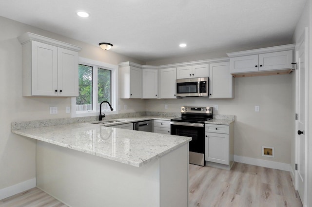1436 W Whiteside St, Springfield, MO 65807 - kitchen with appliances with stainless steel finishes, a sink, a peninsula, light wood-style floors, and light stone counters