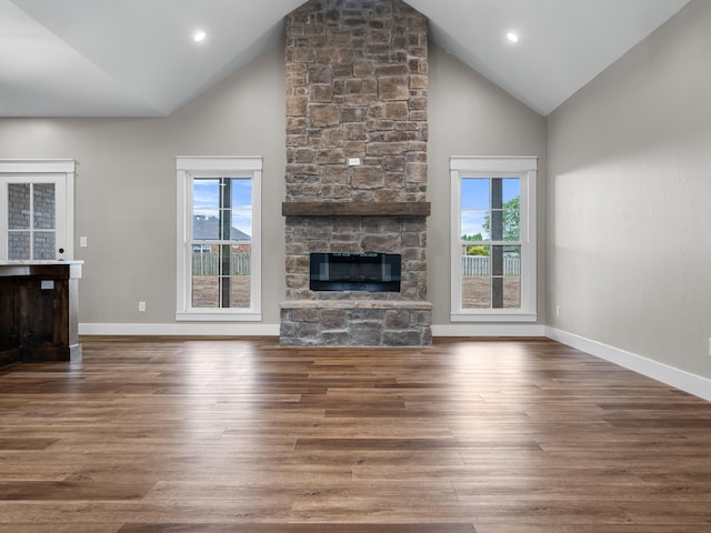 1691 S Charles Pl, Bolivar, MO 65613 - unfurnished living room with wood finished floors, a stone fireplace, high vaulted ceiling, and baseboards