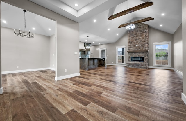 1691 S Charles Pl, Bolivar, MO 65613 - unfurnished living room with dark wood-style floors, beam ceiling, a fireplace, a chandelier, and a sink