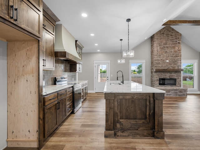 1691 S Charles Pl, Bolivar, MO 65613 - kitchen with electric stove, custom exhaust hood, a sink, a center island with sink, and light wood-style flooring