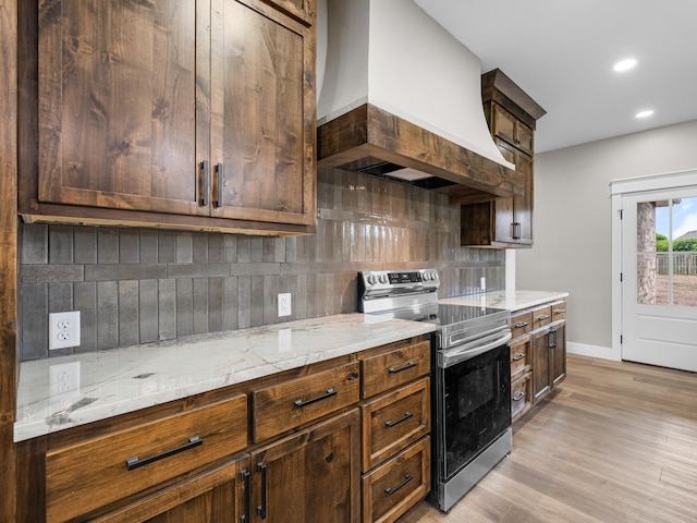 1691 S Charles Pl, Bolivar, MO 65613 - kitchen featuring stainless steel range with electric stovetop, custom exhaust hood, tasteful backsplash, light stone counters, and baseboards