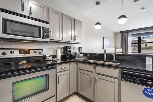 2204A Branson Landing Blvd, Branson, MO 65616 - kitchen featuring stainless steel appliances, a sink, gray cabinetry, dark stone countertops, and hanging light fixtures