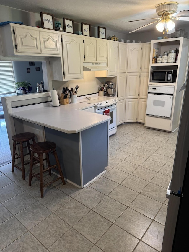 9153 N Hwy Highway, Mountain Grove, MO 65711 - kitchen featuring white appliances, a peninsula, light tile patterned floors, light countertops, and a kitchen bar